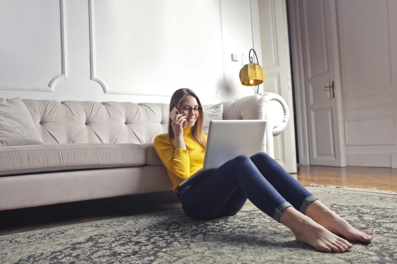 a woman sitting on the floor using a laptop, trending on pexels, yellow clothes, girl making a phone call, velvet couch, long legs