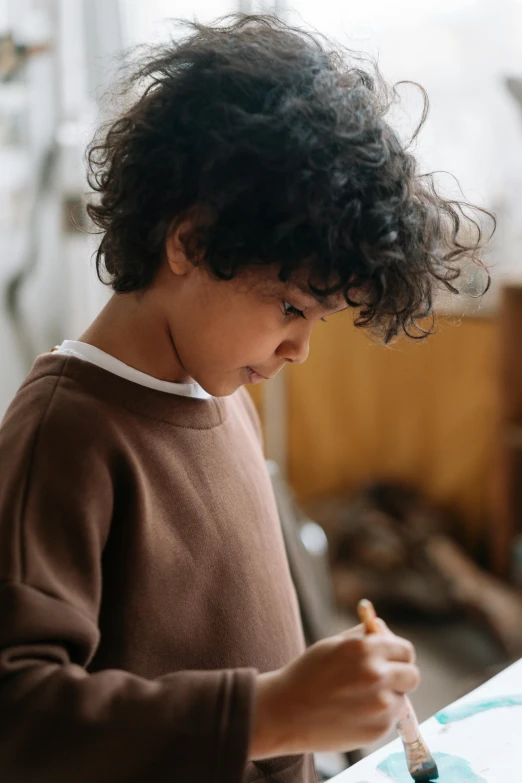 a little boy that is painting on a piece of paper, pexels contest winner, brown sweater, gnarly details soft light, ignant, handsome girl