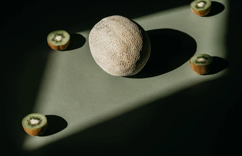 a melon sitting on top of a table next to kiwi, inspired by Elsa Bleda, unsplash contest winner, surrealism, caustics shadows, circle forms, sponge, high quality photo