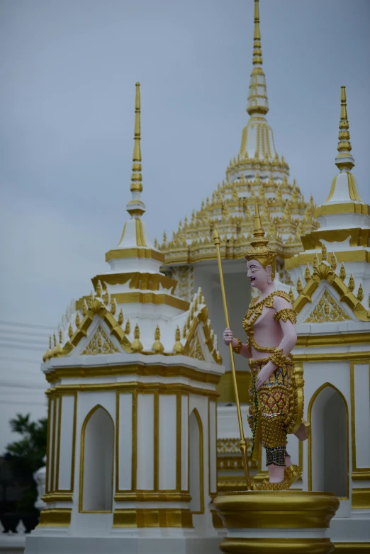 a statue in front of a white and gold building, inspired by Jin Nong, thai, spires, holding spear, 2019 trending photo