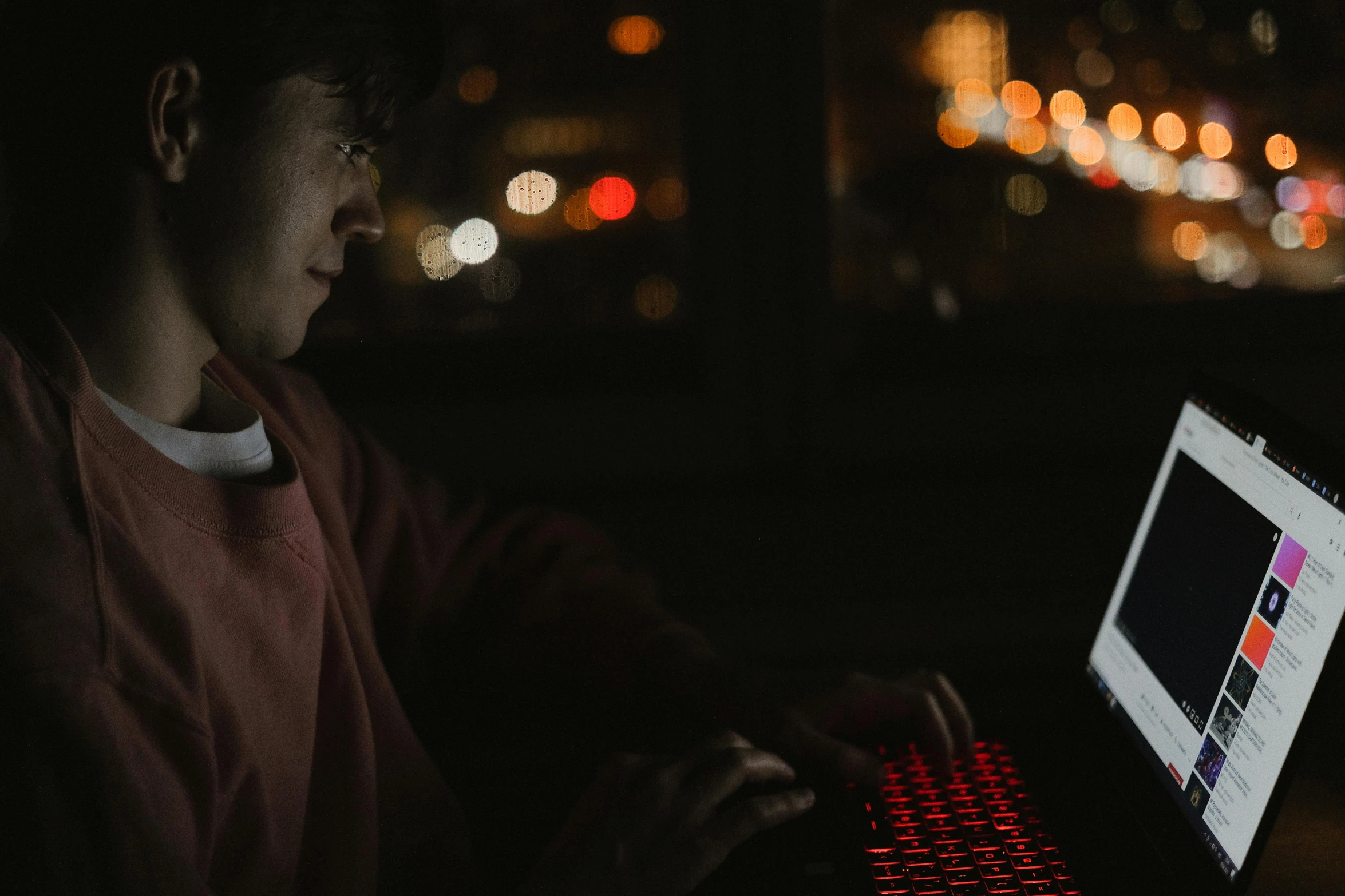 a man using a laptop computer in the dark, trending on pexels, red leds, playing games, during dawn, slightly pixelated