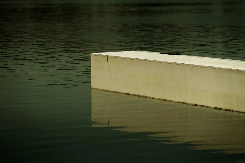 a concrete block in the middle of a body of water, inspired by Rachel Whiteread, unsplash, postminimalism, colour photograph, moored, ignant, lpoty