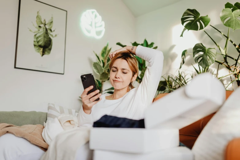 a woman sitting on a bed looking at her phone, trending on pexels, happening, avatar image, skincare, stacked image, covered in plants