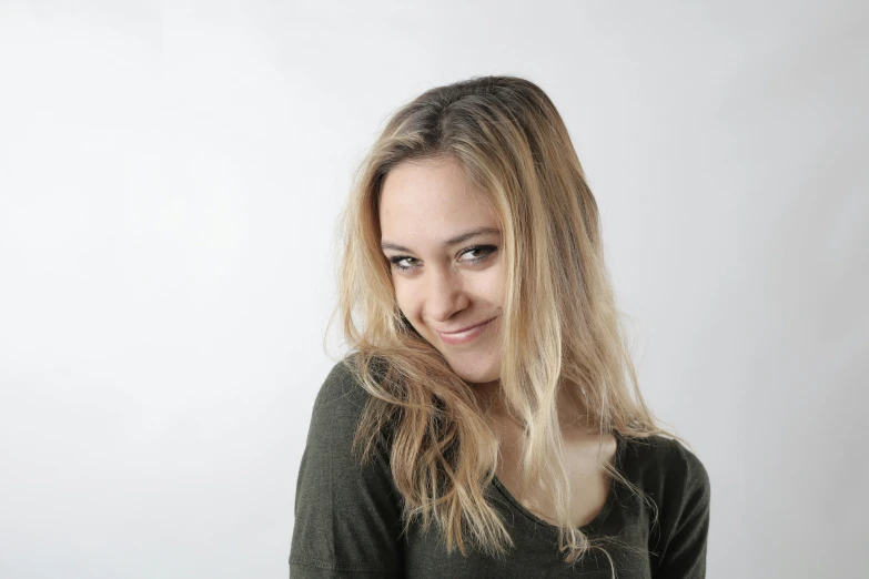 a close up of a person holding a cell phone, blonde medium hair, lovingly looking at camera, in front of white back drop, avatar image