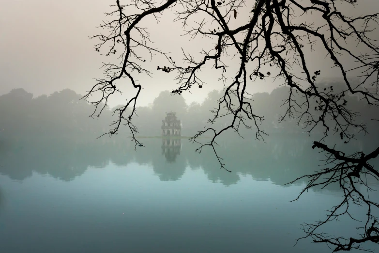 a large body of water surrounded by trees, inspired by Pierre Pellegrini, vietnamese temple scene, grey mist, getty images proshot, album