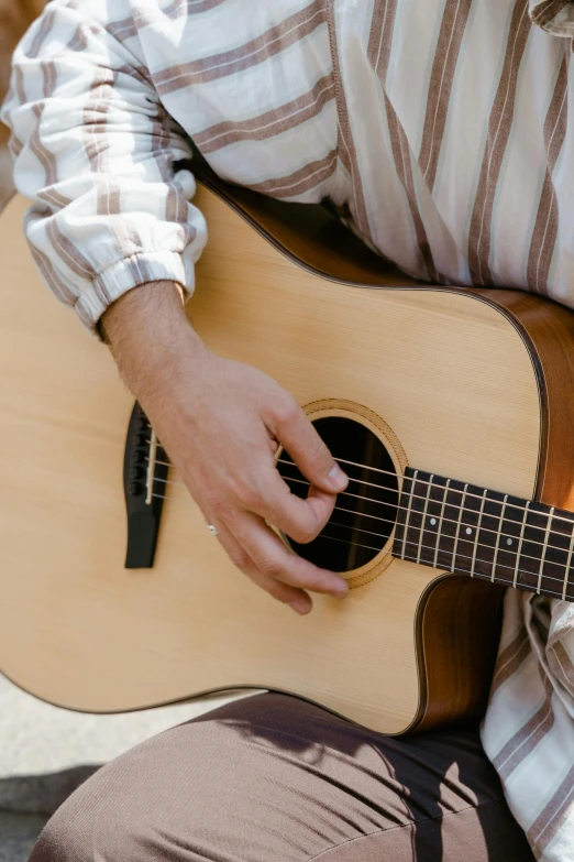 a close up of a person playing a guitar, inspired by James Bard, trending on pexels, light tan, lightly dressed, sunday, oud