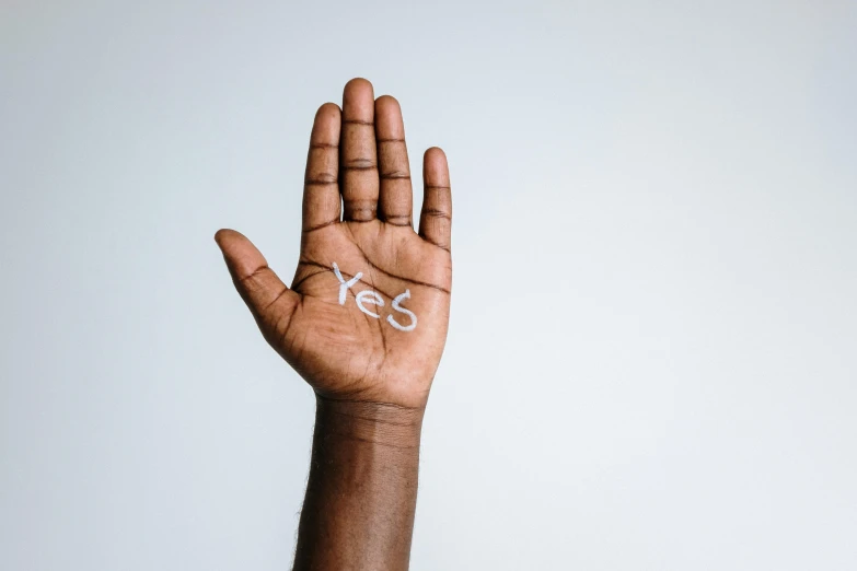 a person's hand with the word yes written on it, trending on pexels, black skin, background image, palm body, brown