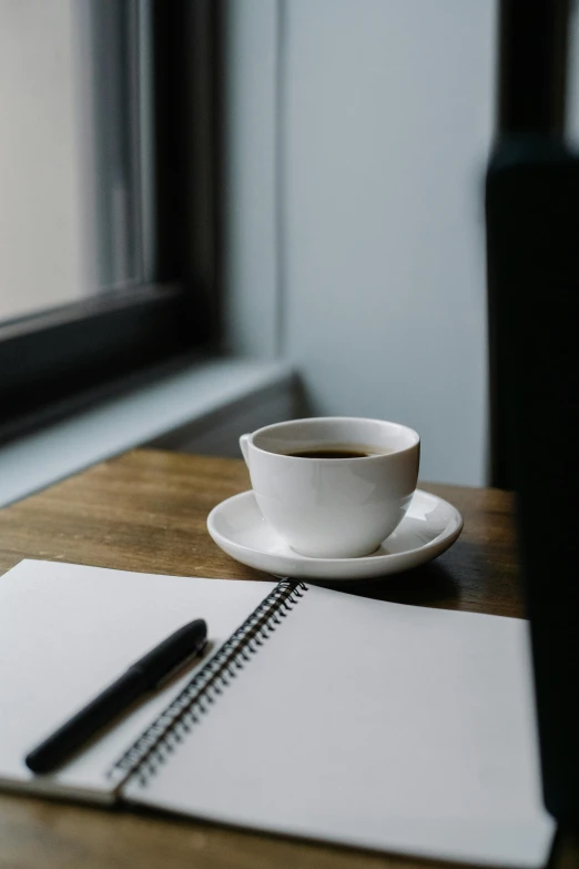 a cup of coffee sitting on top of a wooden table, by Daniel Seghers, unsplash, romanticism, pen on white paper, multiple stories, notebook, background image