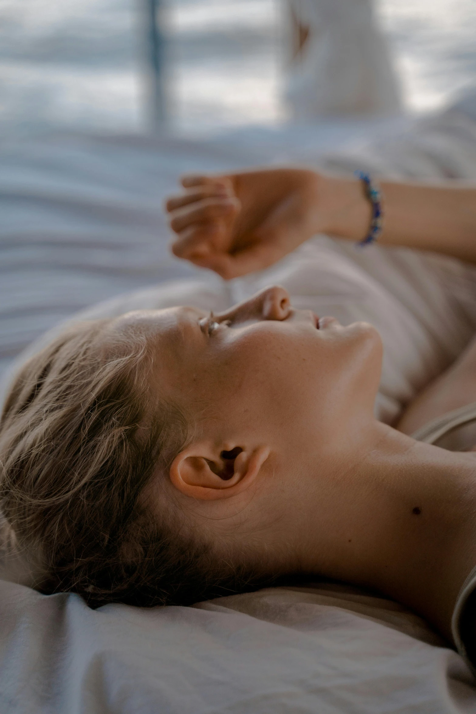 a woman laying on top of a bed next to a window, trending on pexels, acupuncture treatment, dreaming face, play of light, hyperdetailed