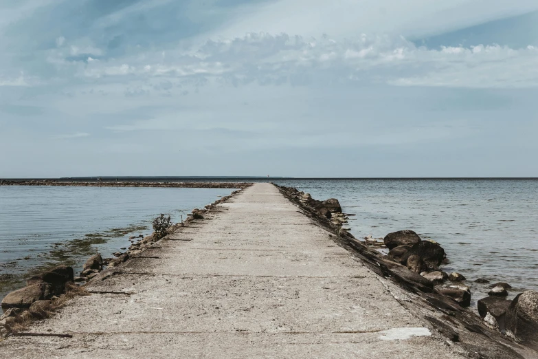 a pier in the middle of a body of water, unsplash, minimalism, background image, road to the sea, ruins around, brown