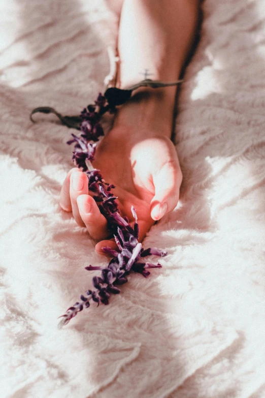 a person laying on a bed with a flower in their hand, trending on pexels, purple ribbons, limbs made from vines, holding hands, salvia