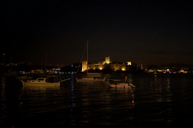 a group of boats sitting on top of a body of water, by Daniel Seghers, pexels contest winner, hurufiyya, dark castle setting, night cam footage, harbour in background, portrait mode photo