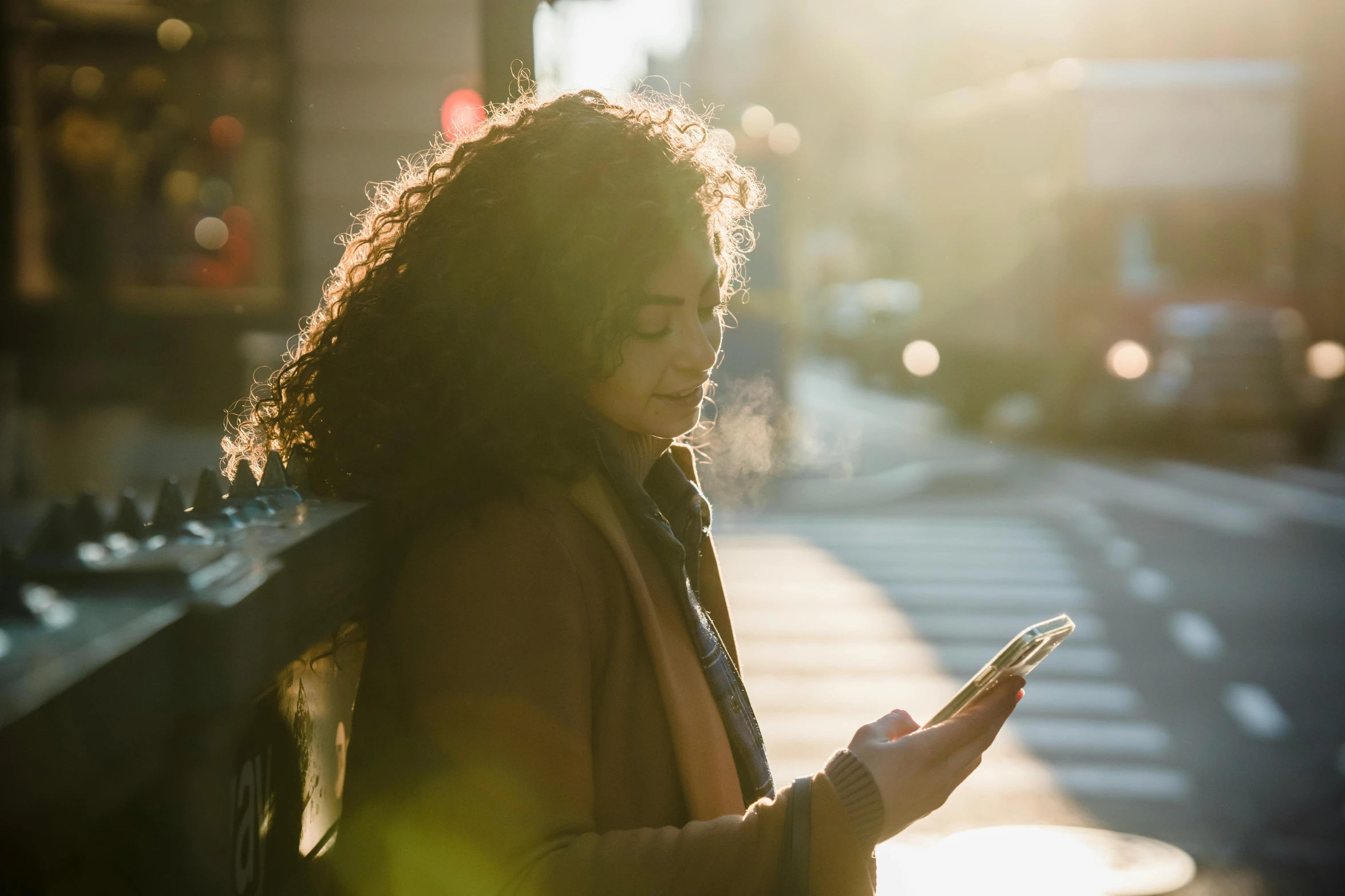 a woman standing on a city street looking at her cell phone, trending on pexels, warm sunlight shining in, hispanic, waiting, february)