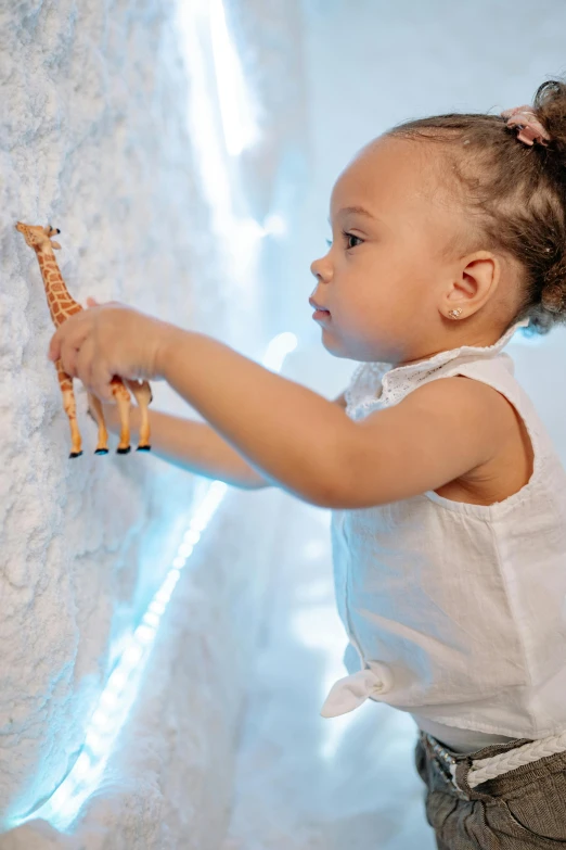 a little girl that is playing with a giraffe, interactive art, in an icy cavern, white marble interior photograph, tactile buttons and lights, wall art