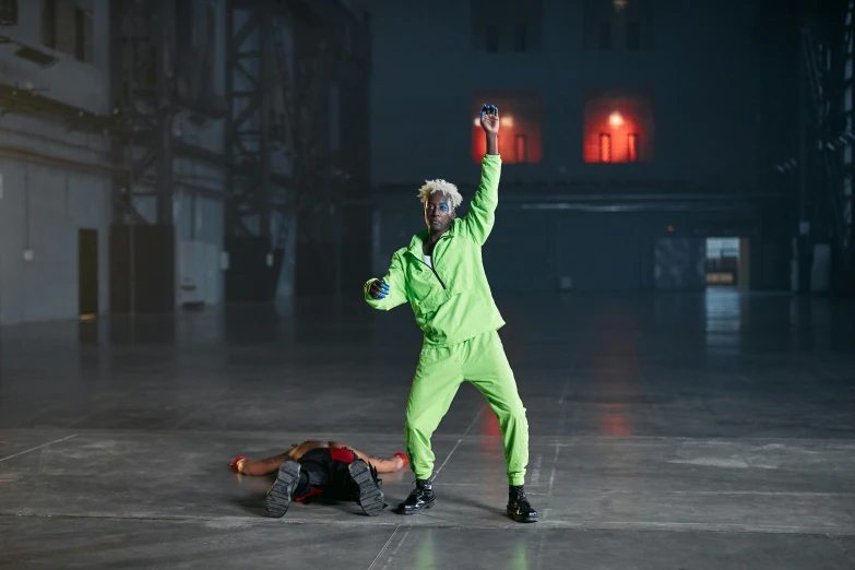 a man in a green suit doing a trick on a skateboard, inspired by Mike Winkelmann, wearing cyberpunk 2 0 7 7 jacket, die antwoord music video, stood in a factory, playboi carti and lil uzi vert