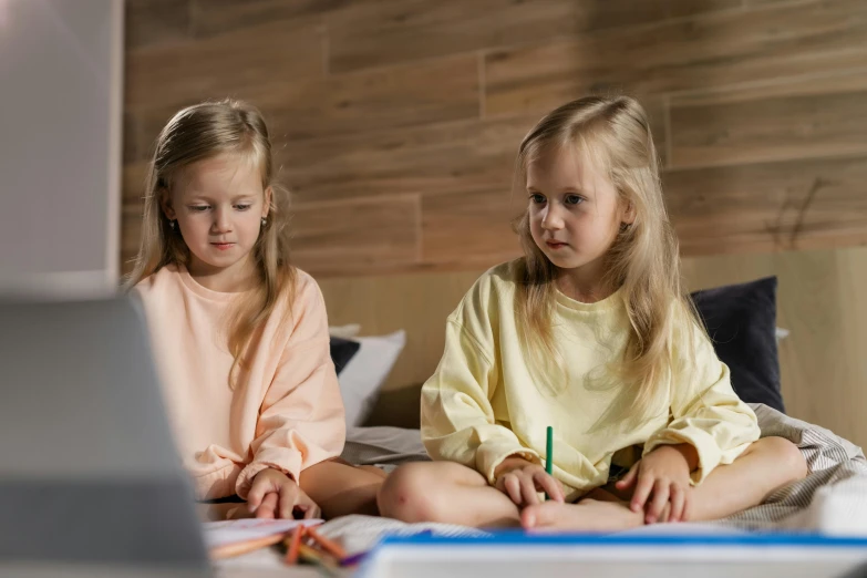 a couple of little girls sitting on top of a bed, a child's drawing, trending on pexels, twins playing video games, school curriculum expert, evening time, lachlan bailey