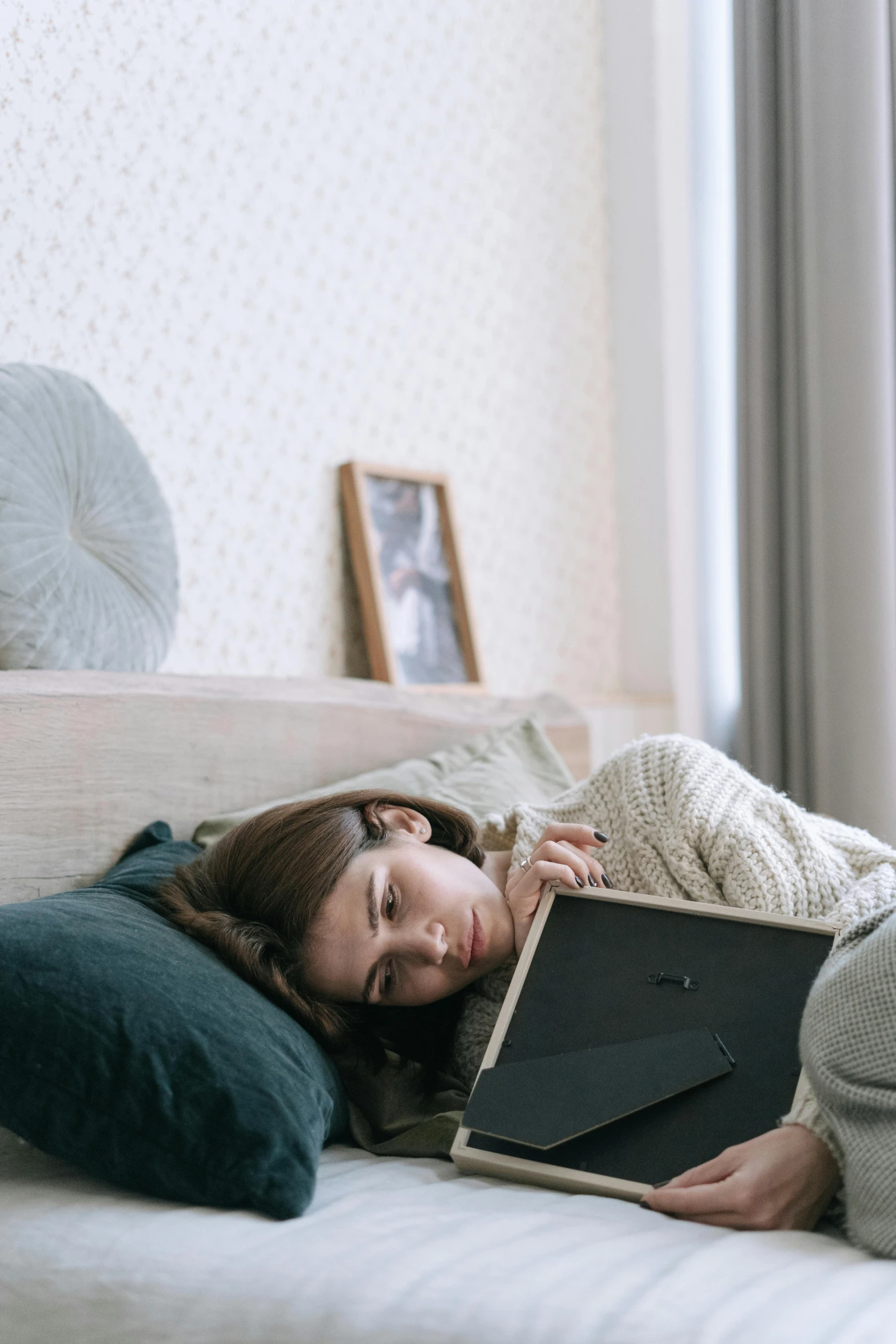 a woman laying on a bed reading a book, inspired by Elsa Bleda, trending on pexels, sad prisoner holding ipad, tired face, grey, gif