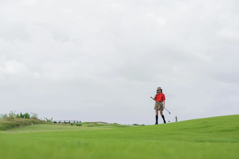 a man standing on top of a lush green field, clubs, whealan, girl walking between dunes, wearing a red captain's uniform