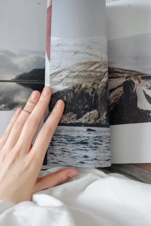 a person laying in bed reading a book, photorealism, nordic wedding ring, soft-sanded coastlines, old photobook, closeup of hand