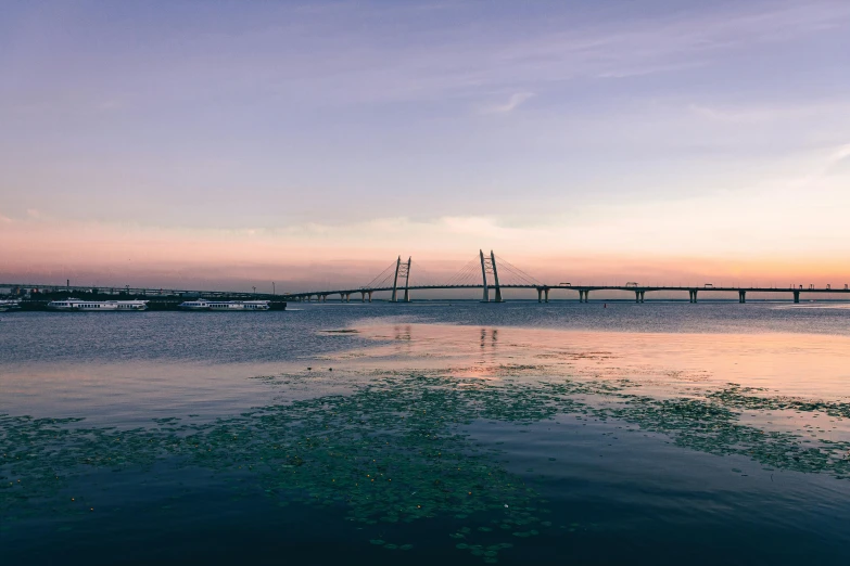 a body of water with a bridge in the background, pexels contest winner, hurufiyya, calcutta, skies behind, day setting, with a long
