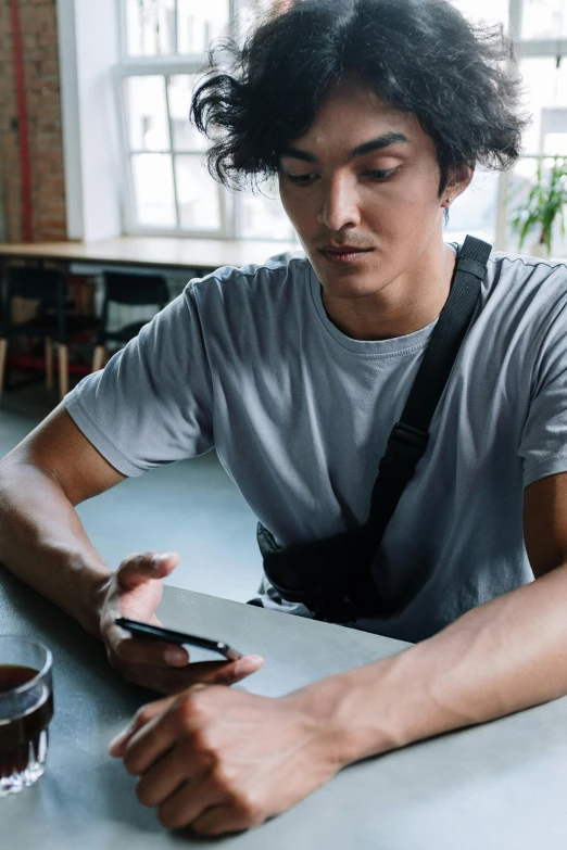 a man sitting at a table with a cell phone, inspired by John Luke, trending on pexels, asian male, thumbnail, studious, waist up