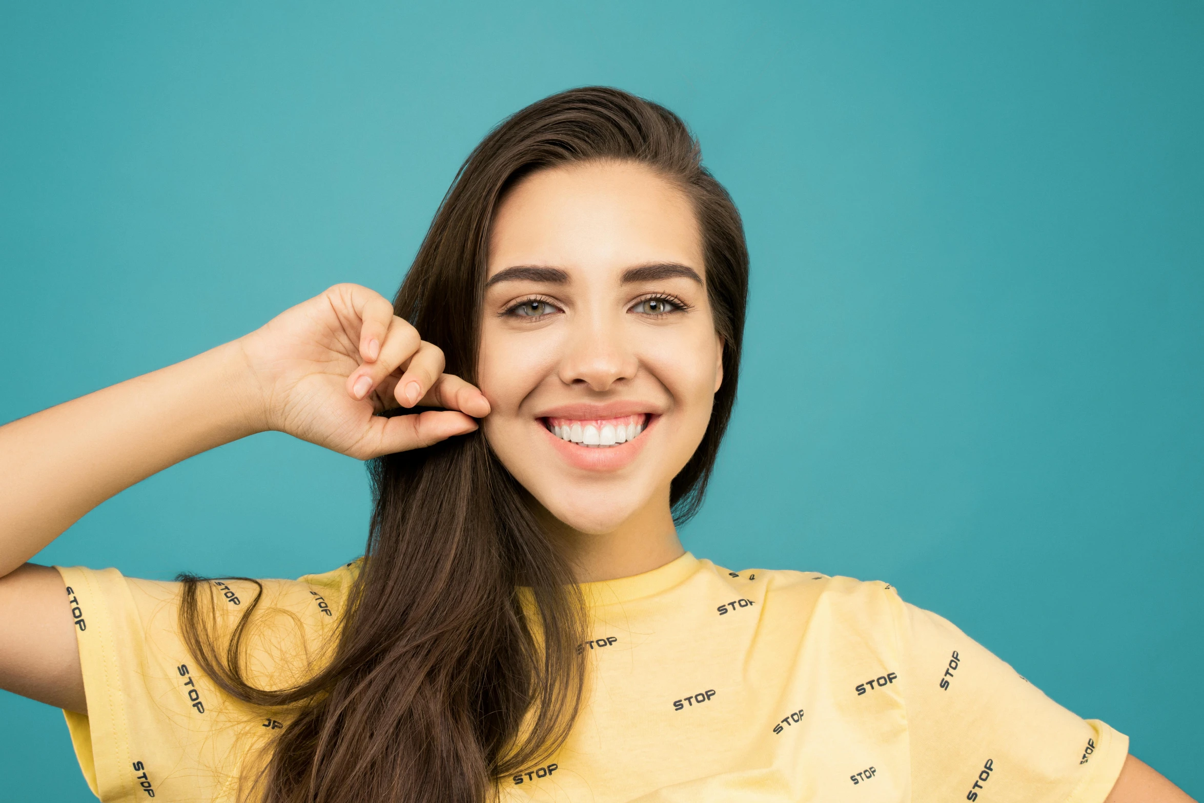 a woman with long brown hair wearing a yellow shirt, trending on pexels, antipodeans, she has perfect white teeths, avatar image, pointè pose, underbite