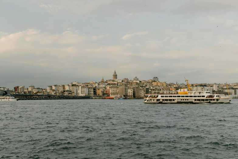 a boat on a body of water with a city in the background, by Elsa Bleda, pexels contest winner, hurufiyya, turkey, olafur eliasson, slide show, grey