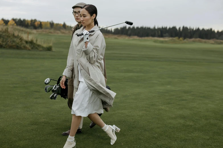 a man and a woman walking on a golf course, a portrait, by Emma Andijewska, pexels contest winner, bauhaus, li bingbing, trenchcoat, thumbnail, angelina stroganova