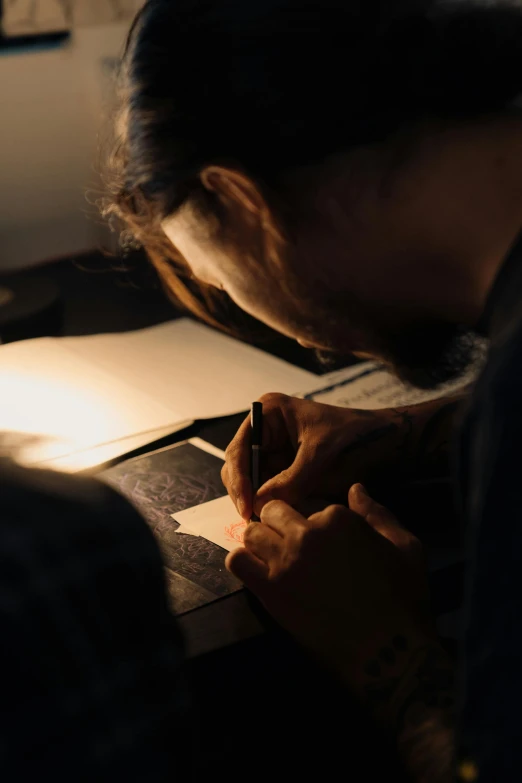 a woman sitting at a desk writing on a piece of paper, by artist, pexels contest winner, process art, sun behind him, on black paper, carving, takayuki takeya
