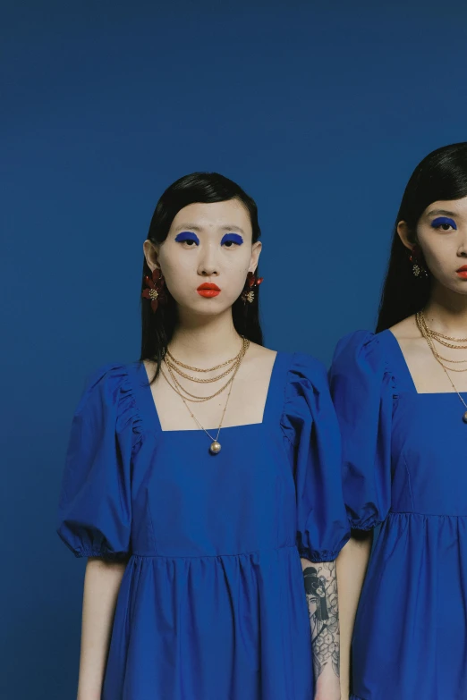 two women in blue dresses standing next to each other, inspired by Vanessa Beecroft, pop surrealism, asian face, biopunk toys made in china, visible pupils, with a twin