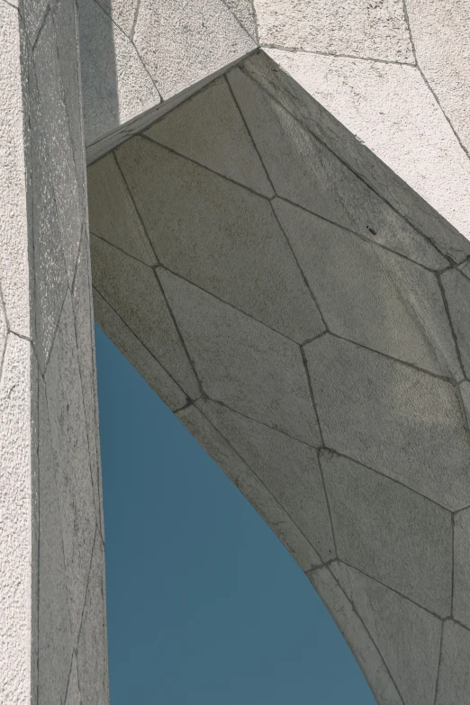 a white building with a blue sky in the background, inspired by Ned M. Seidler, unsplash, concrete art, fractal details diamond skin, rock arches, detail shot, gray concrete