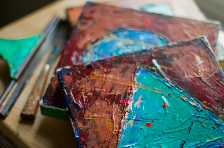 a close up of a piece of art on a table, inspired by Hans Hofmann, pexels, brown red blue, teal silver red, palettes, candid shot