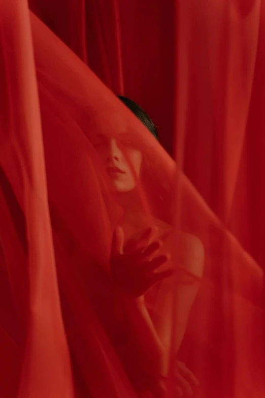 a woman sitting on top of a red cloth, inspired by Elsa Bleda, pexels contest winner, magic realism, face obscured, film still from the movie, diaphanous iridescent silks, red flags