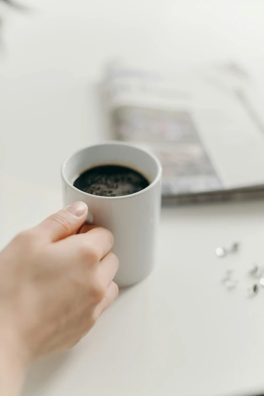 a close up of a person holding a cup of coffee, private press, on a white table, with sparkling gems on top, uncluttered, 6 : 3 0 am