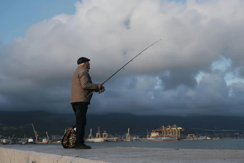 a man standing on a pier holding a fishing rod, pexels contest winner, full body profile, overcast! cinematic focus, harbour in background, yan gisuka