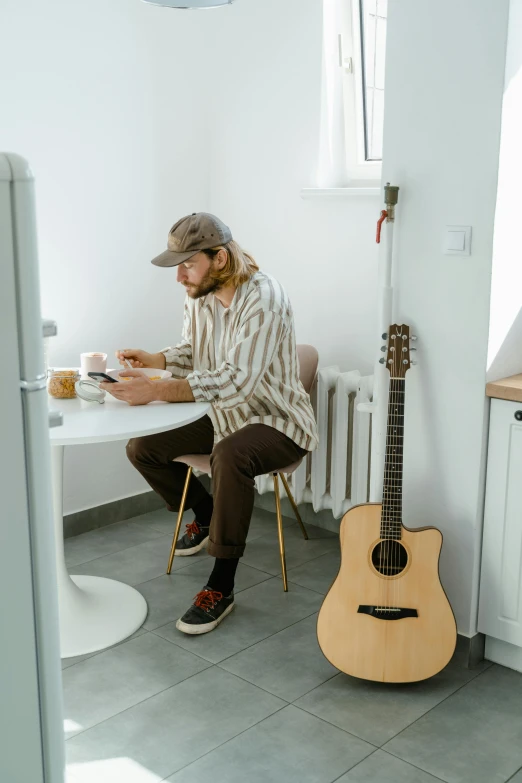 a man sitting at a table with a guitar, trending on pexels, full-body, wearing a linen shirt, morning coffee, felix englund