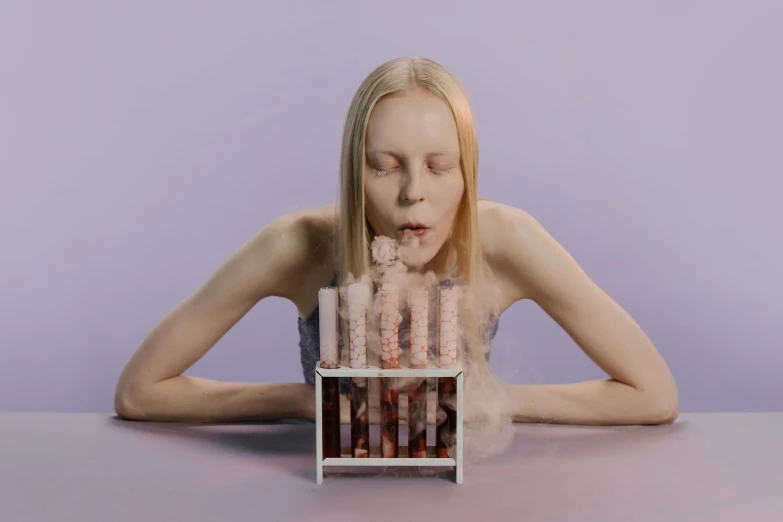 a woman sitting at a table with a cake in front of her, an album cover, inspired by Vanessa Beecroft, pexels contest winner, conceptual art, smoke columns, modeling photograph kerli koiv, patricia piccinini, mini model