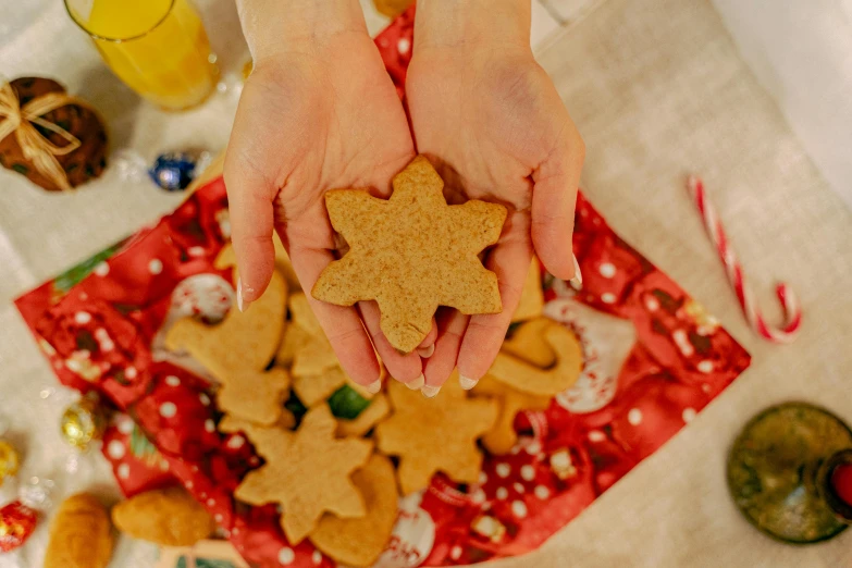 a person holding a cookie in their hands, by Julia Pishtar, pexels contest winner, folk art, twinkling stars, ginger, 6 pack, 🍸🍋
