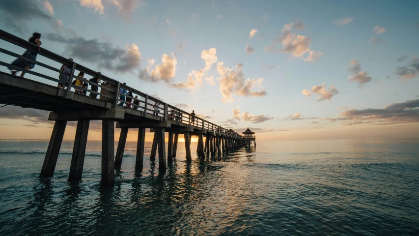 a couple of people that are standing on a pier, by Niko Henrichon, pexels contest winner, renaissance, florida man, viewed from the ocean, late afternoon sun, epic ultrawide shot