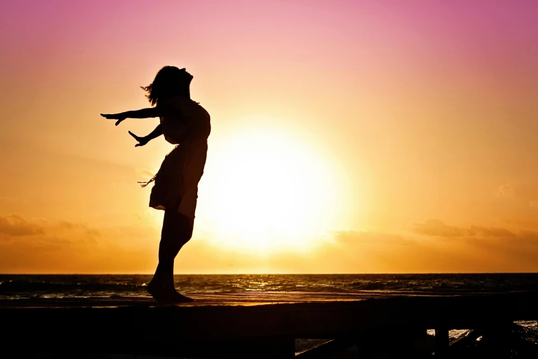 a silhouette of a person standing on a pier at sunset, pexels, dancing on the beach, happy girl, profile image, compassionate