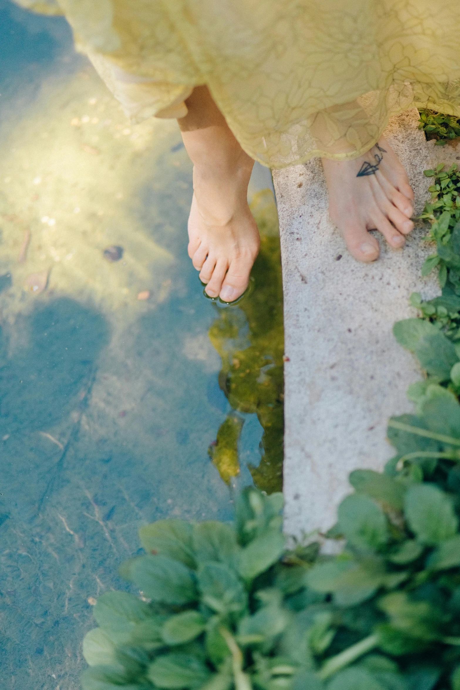 a woman in a yellow dress standing next to a body of water, unsplash, renaissance, real human feet, gardening, floating. greenish blue, ignant