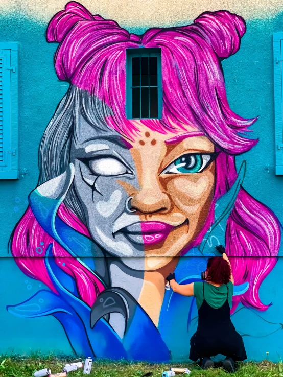 a woman painting a mural on the side of a building, graffiti art, by NEVERCREW, pexels contest winner, pink and blue hair, symmetry face, lesbian art, photo of a painting