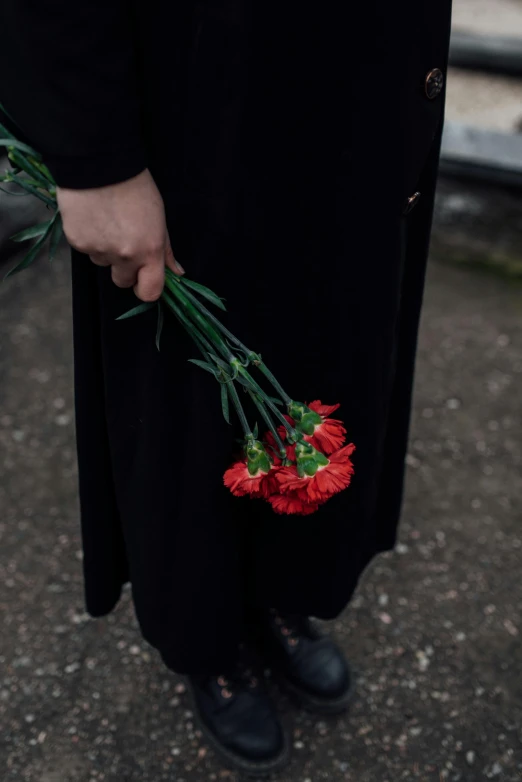 a person holding a bunch of red flowers, by Anna Boch, unsplash, wearing black robes, heartbreak, ignant, cementary