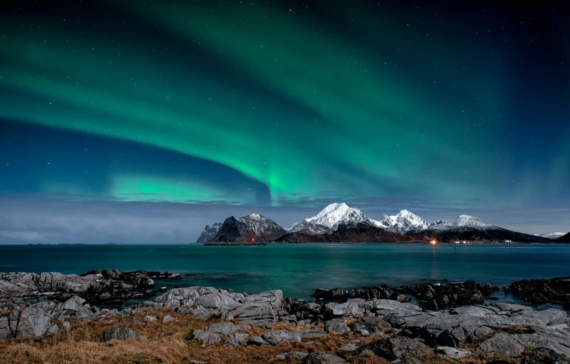 a large body of water with a mountain in the background, by Julia Pishtar, pexels contest winner, romanticism, northen lights background, mountains and ocean, thumbnail, multiple stories