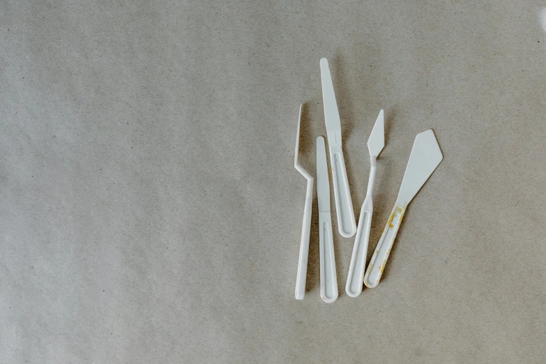 a group of plastic utensils sitting on top of a table, a still life, by Adam Marczyński, unsplash, plasticien, steel blades, cream paper, low quality photo, close-up product photo