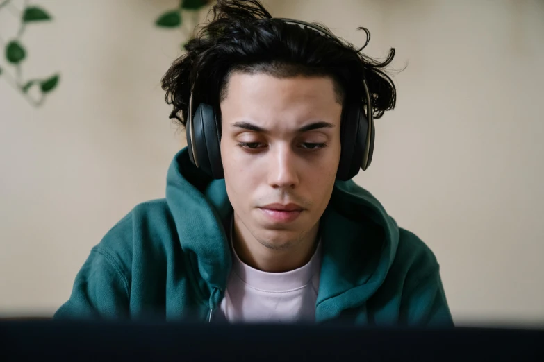 a man sitting in front of a computer wearing headphones, trending on pexels, wearing green jacket, pokimane, avatar image, student