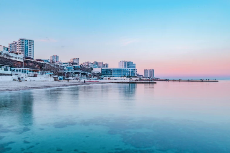 a large body of water next to a beach, inspired by Elsa Bleda, pexels contest winner, city of pristine colors, marsden, city morning, pink white turquoise