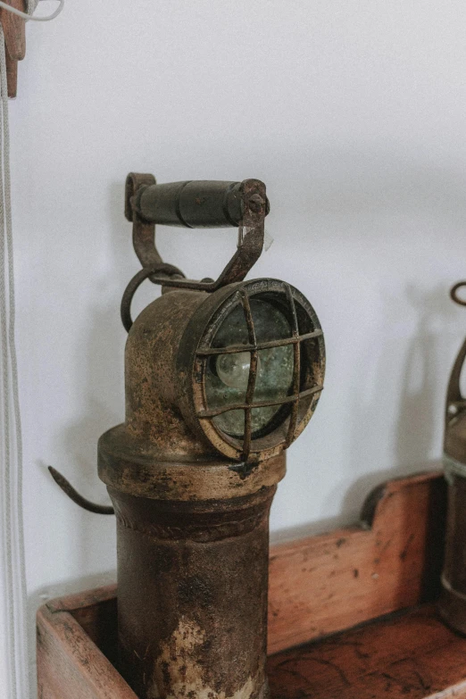 a couple of old lamps sitting on top of a wooden box, rusty helmet, detailed product image, side view close up of a gaunt, search lights