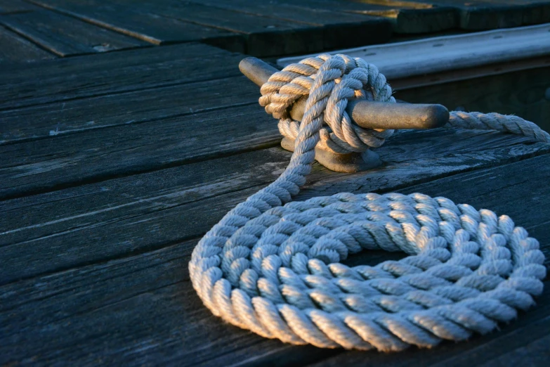 a rope sitting on top of a wooden dock, inspired by Horatio Nelson Poole, pexels contest winner, thumbnail, tubing, islamic, white