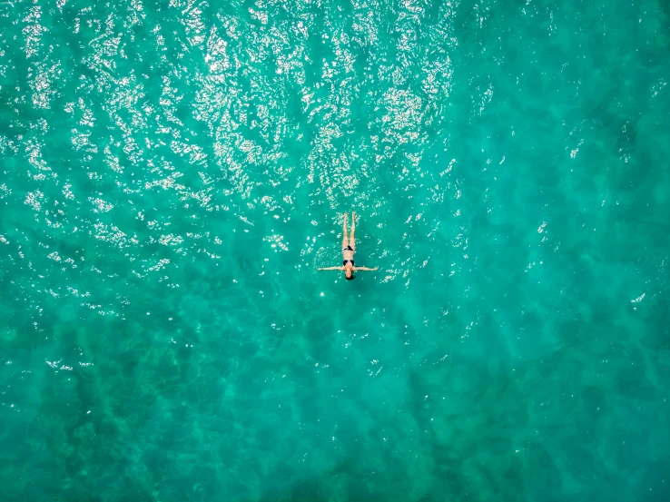 a person laying on a surfboard in the middle of the ocean, inspired by Elsa Bleda, pexels contest winner, helicopter view, teal skin, holiday season, profile pic